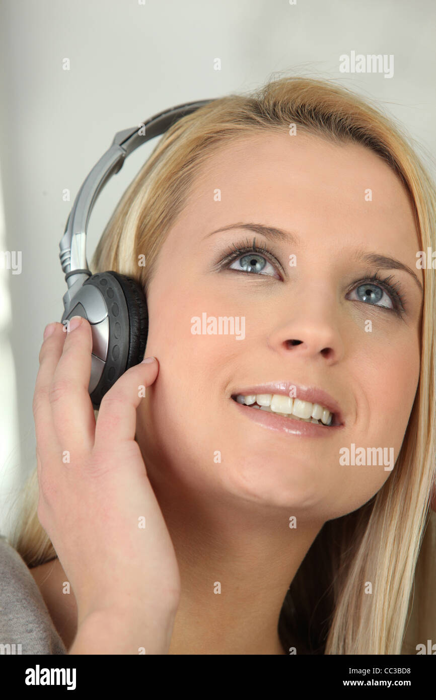 Blond girl listening to music through headphones Stock Photo Alamy