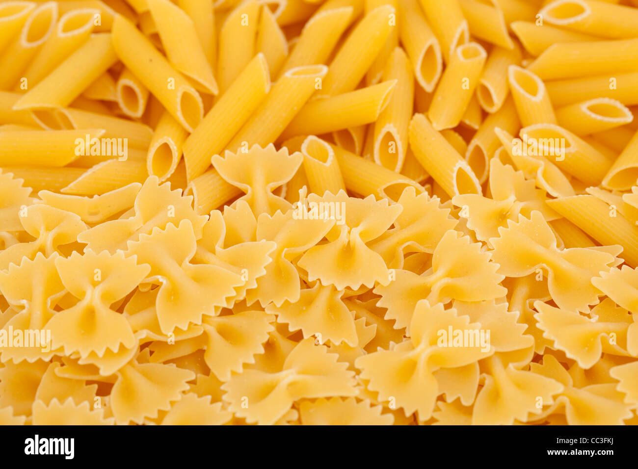 dry yellow pasta farfalle and penne as background Stock Photo
