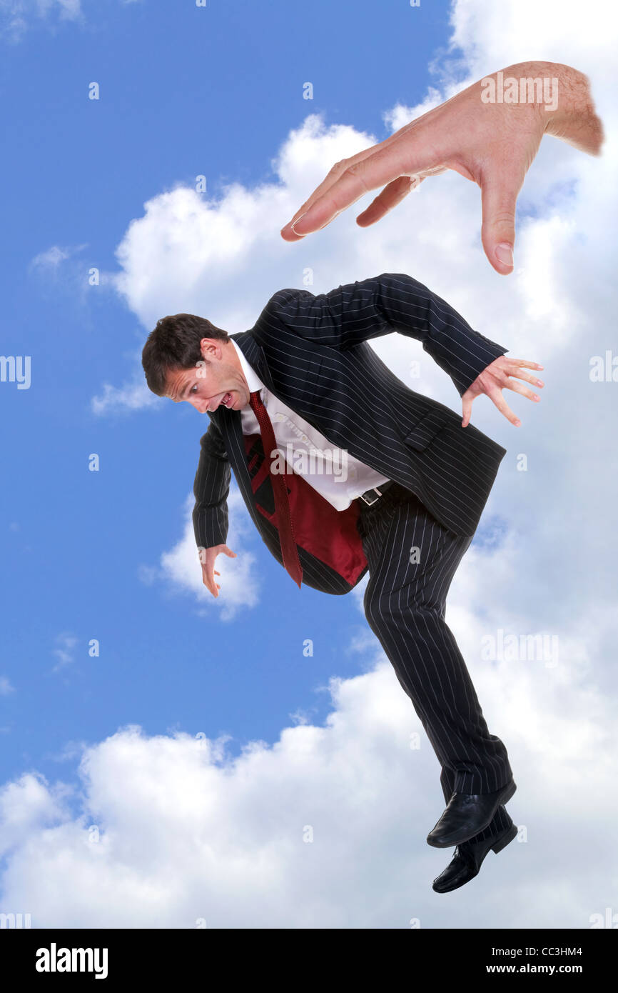 Concept photo of a businessman being dropped out of the sky by the hand of God Stock Photo