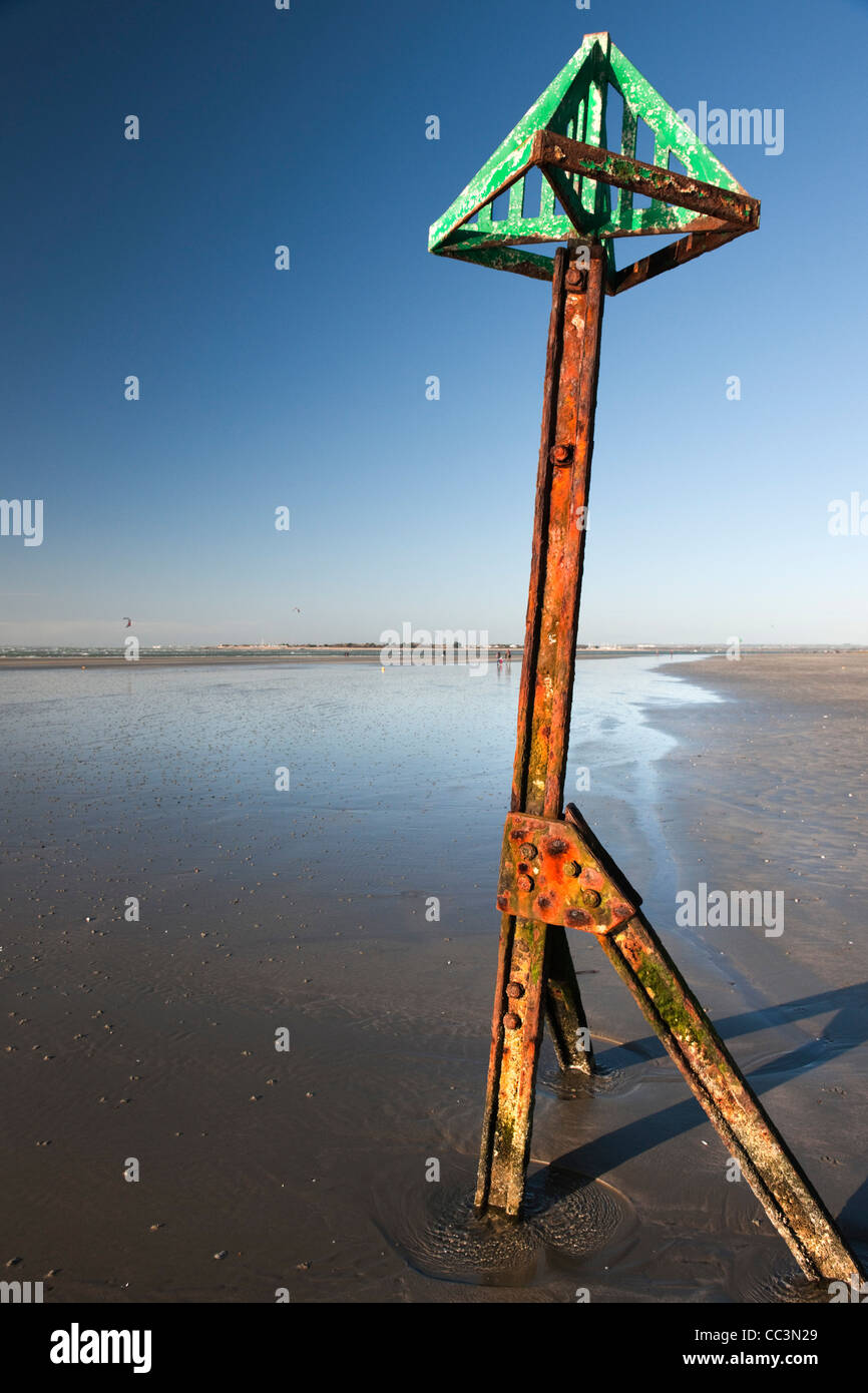 Rusting high tide marker on West Wittering beach with blue sky on a ...