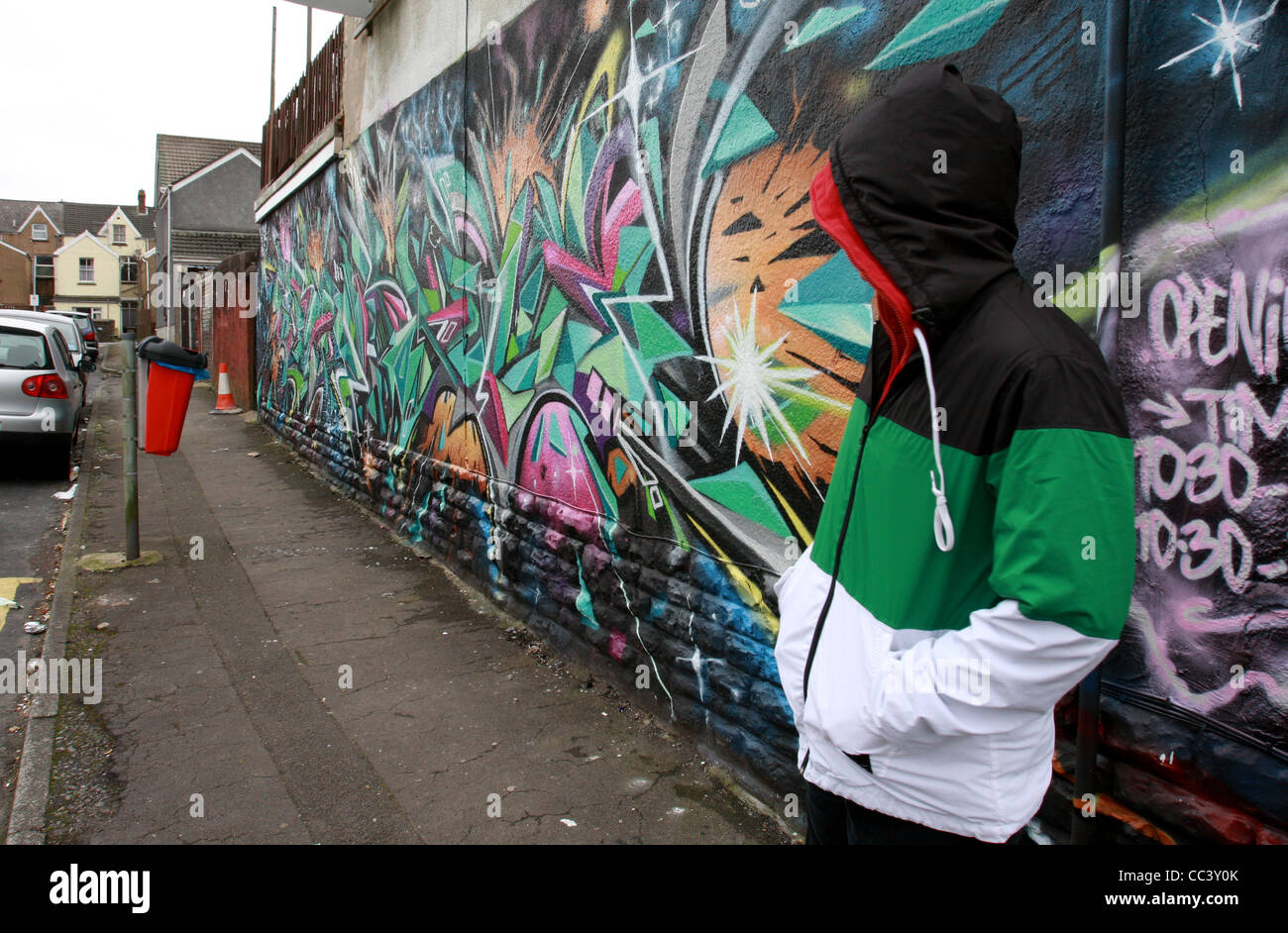 A graffiti writer poses anonymously wearing a hooded jacket infornt of