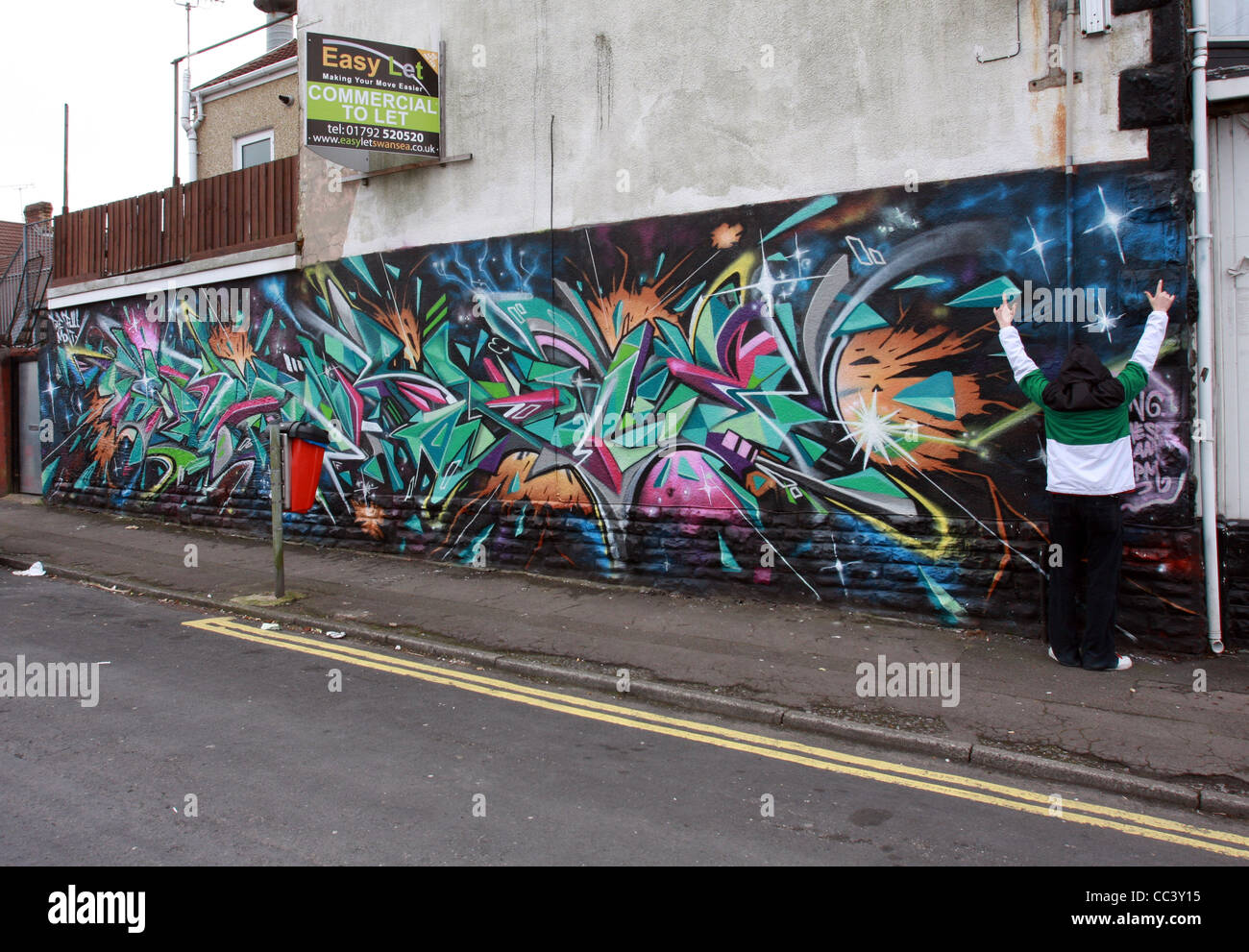 A graffiti writer poses anonymously wearing a hooded jacket infront of