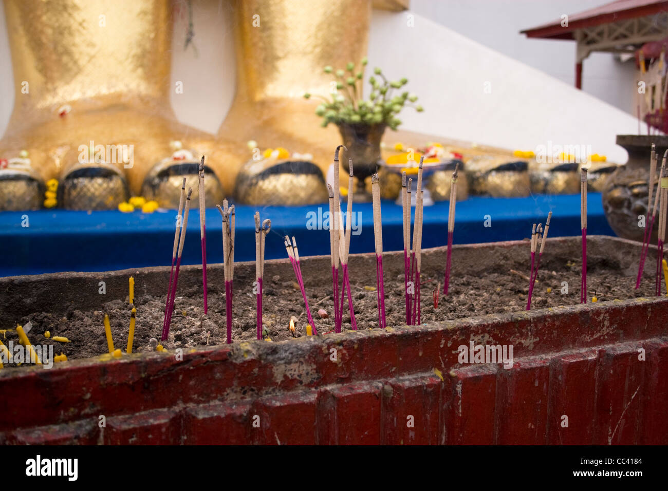 Incense at the feet of the giant standing Buddha at Wat Intharawihan in Bangkok. Stock Photo