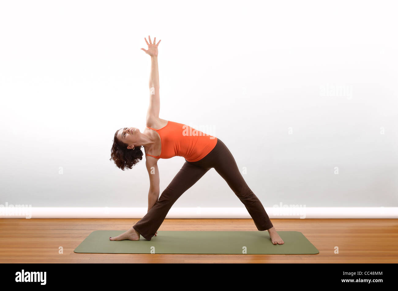 A woman demonstrates the Triangle position in yoga. Stock Photo
