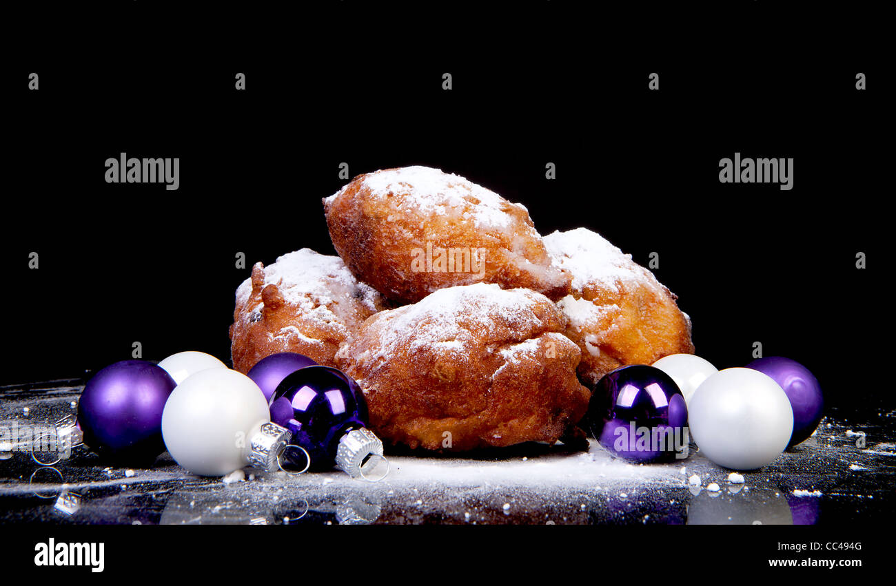 Pile of Dutch oliebollen and Christmas balls over black background Stock Photo