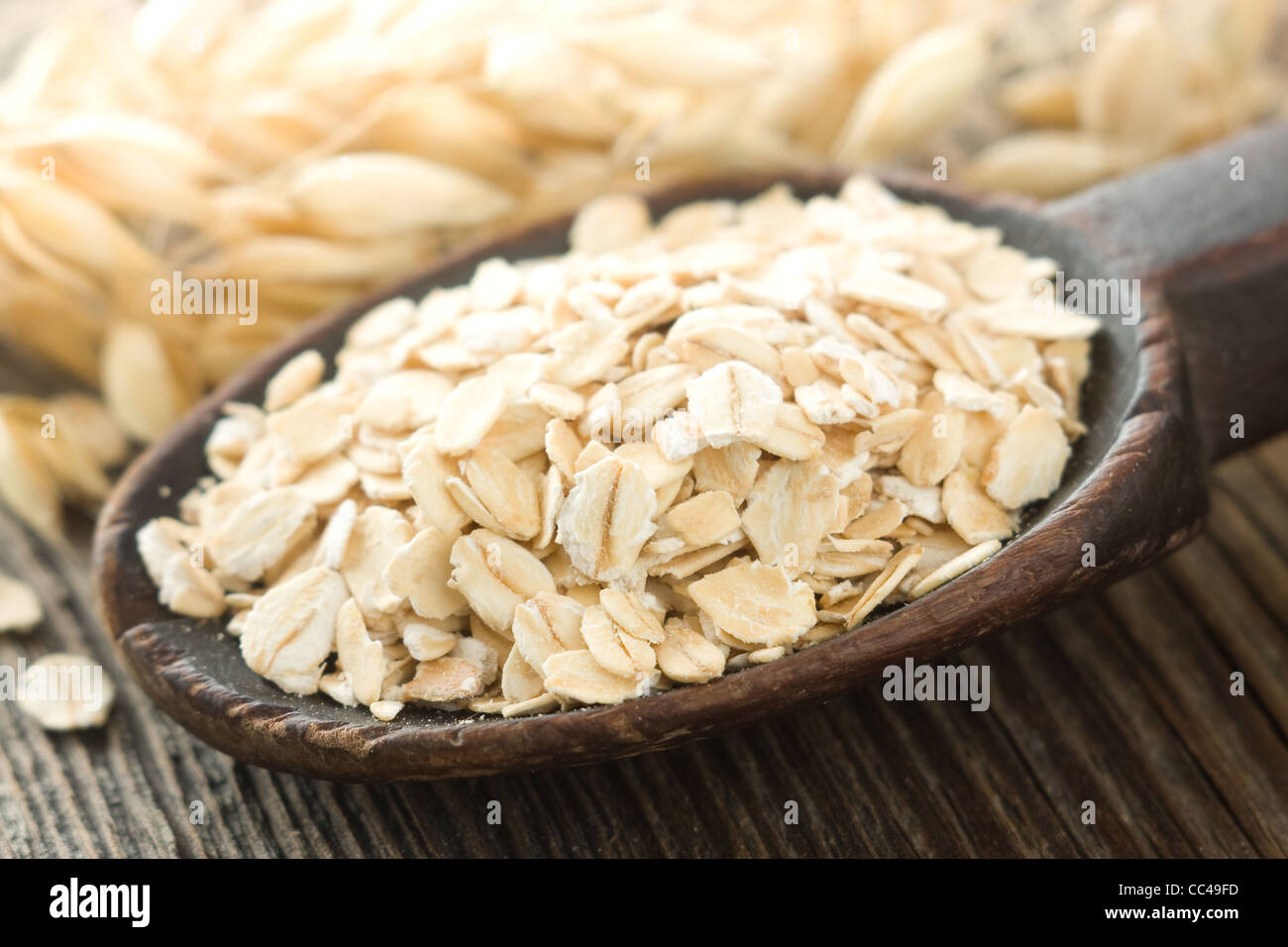 Oatmeal in old wooden spoon Stock Photo
