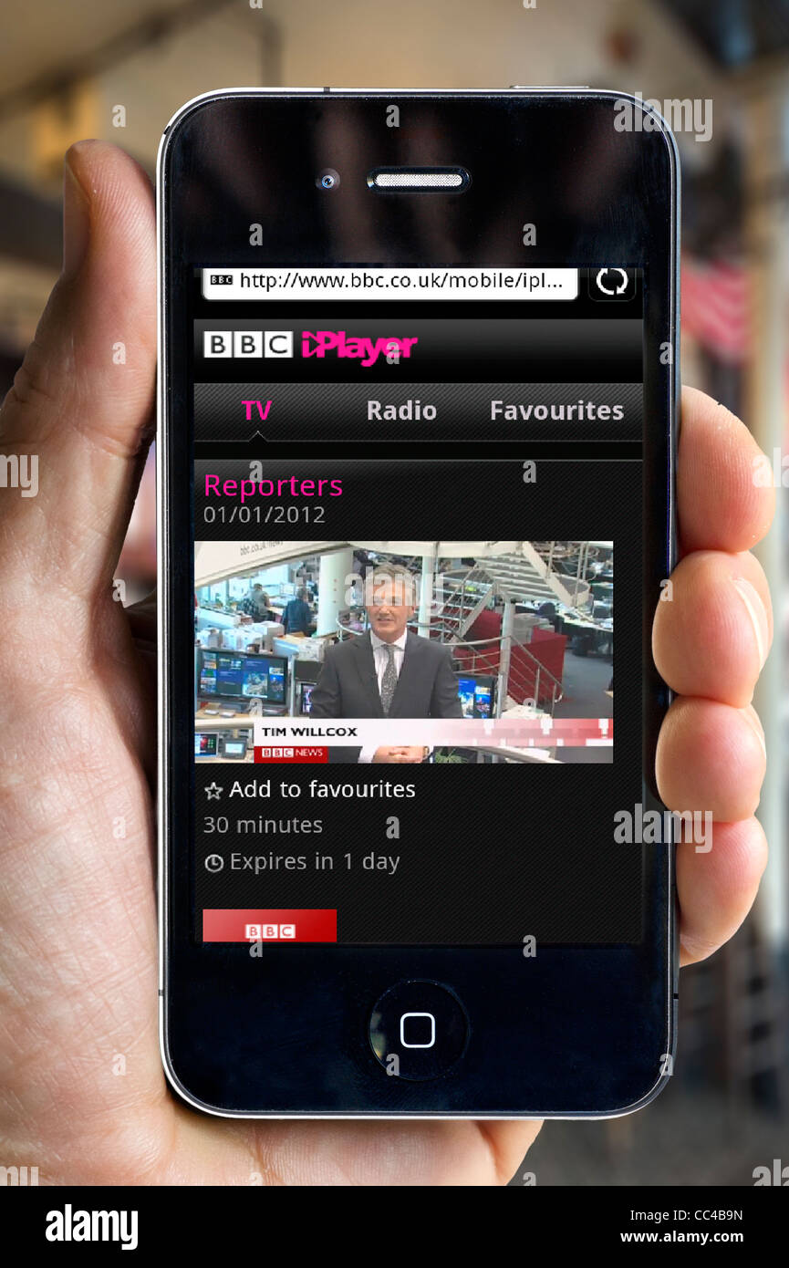 Watching the BBC News Channel on the BBC iPlayer on an Apple iPhone 4 smartphone via a public Wi-Fi hotspot Stock Photo