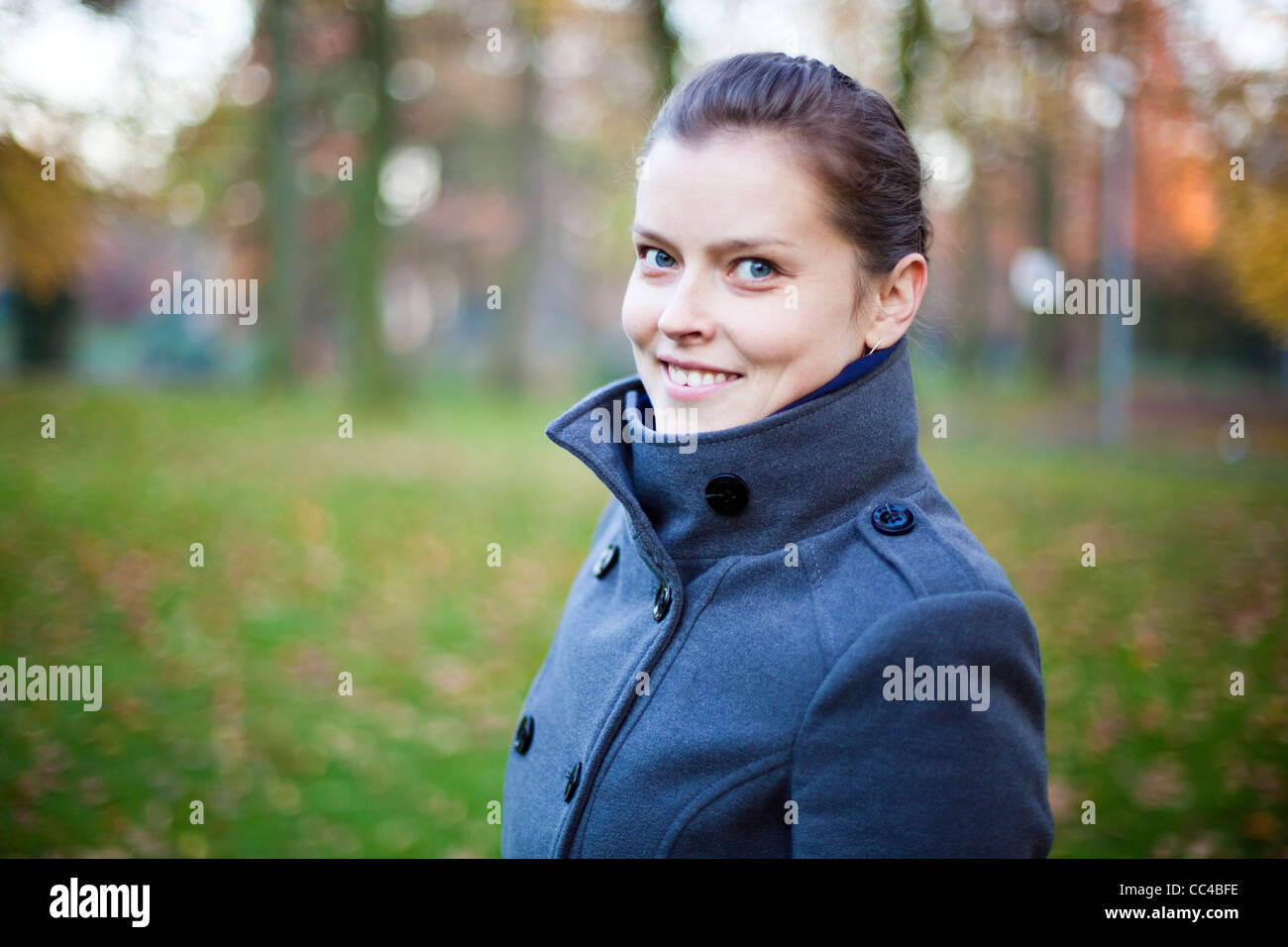 A girl with blue eyes smiling at the camera. She is wearing a blue gray ...