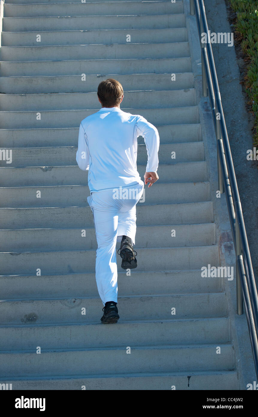 A man dressed in all white running up stairs. Stock Photo
