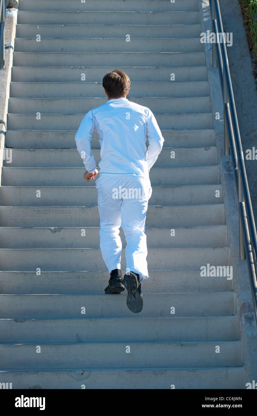 A man dressed in all white running up stairs. Stock Photo