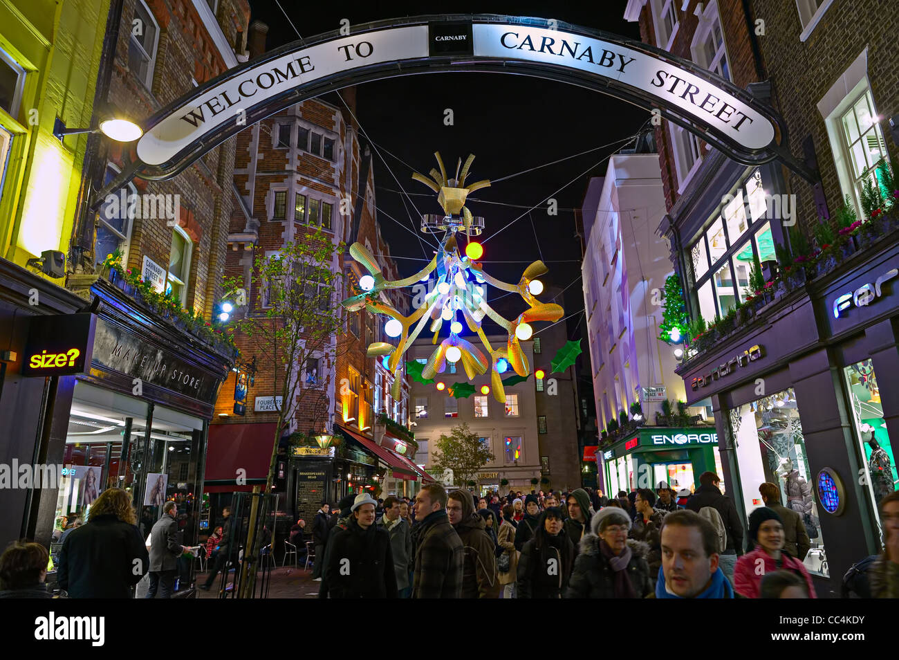 Carnaby Street full of Christmas shoppers, London, England, UK, with festive decorative lights at night Stock Photo