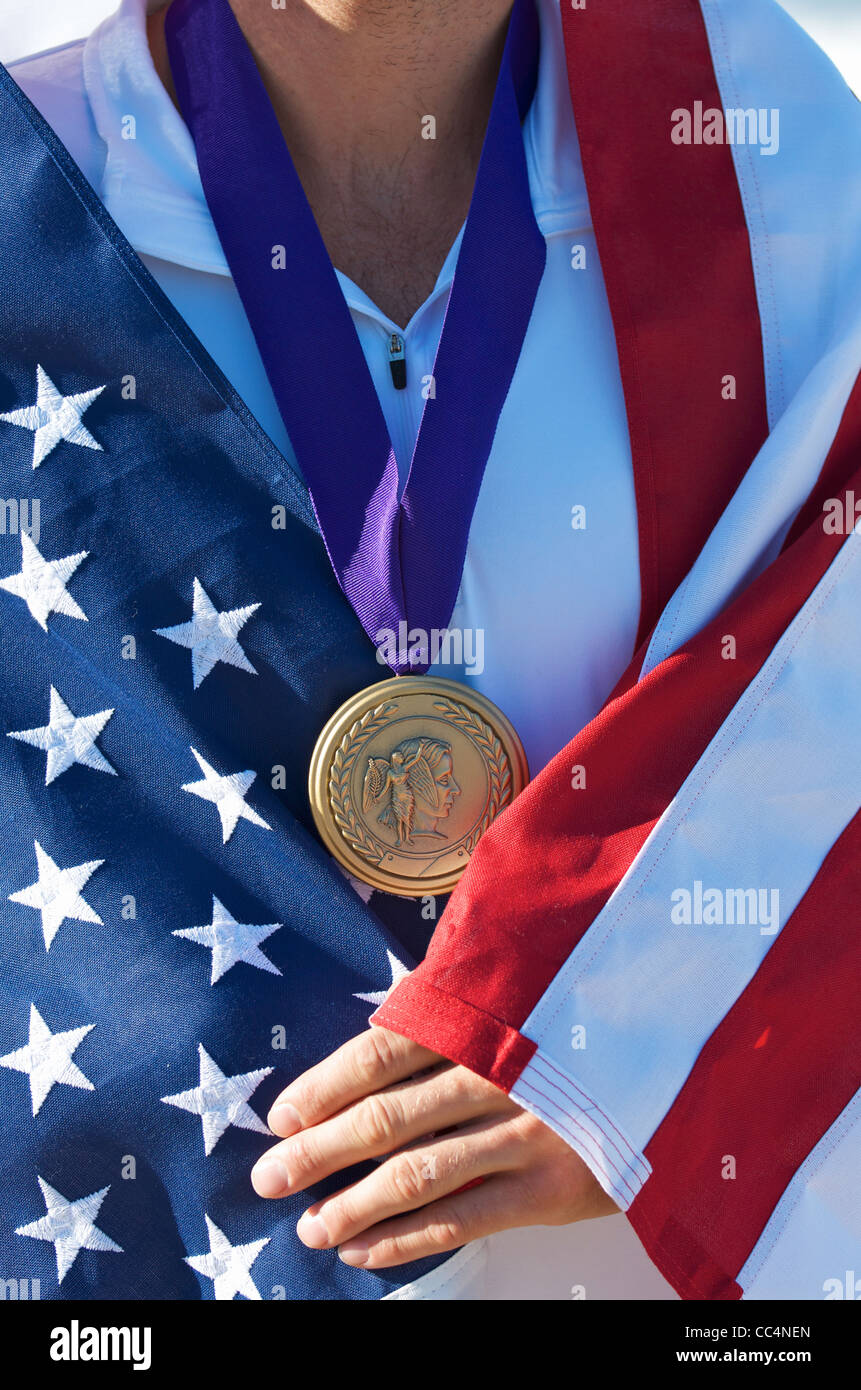Portrait of a man with an American flag and Olympic gold medal (simulated) on the beach. Stock Photo