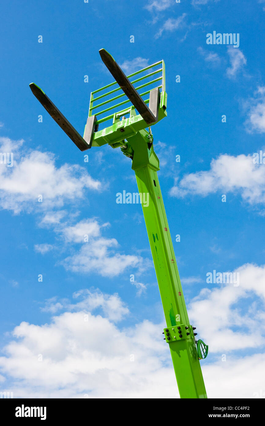 Green Telescopic Hydraulic Forks Towering Against Bright Blue Sky Stock Photo