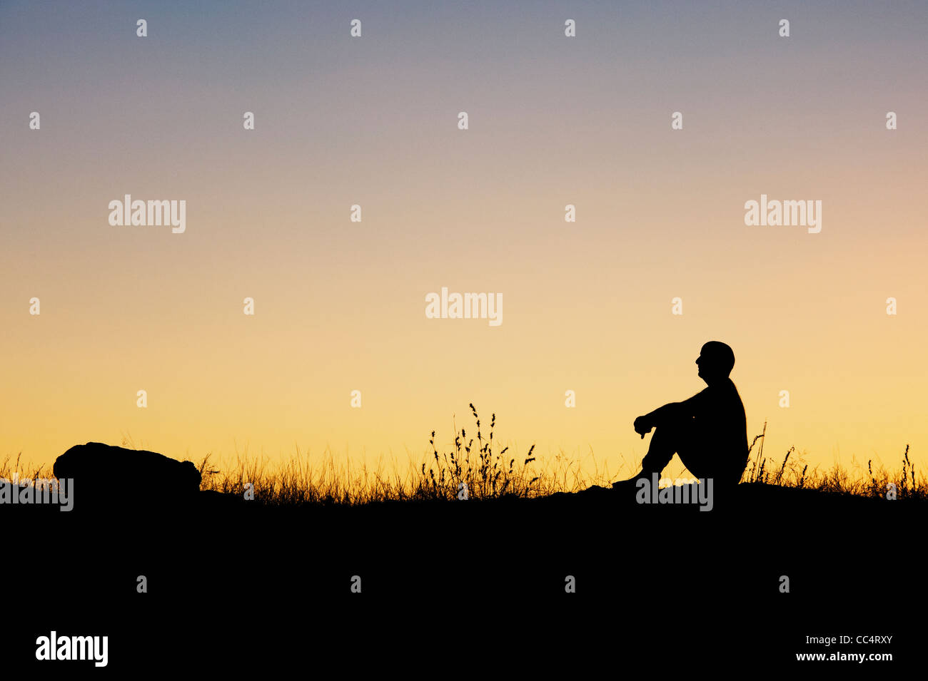 Man sitting in the indian countryside at dawn. Silhouette Stock Photo