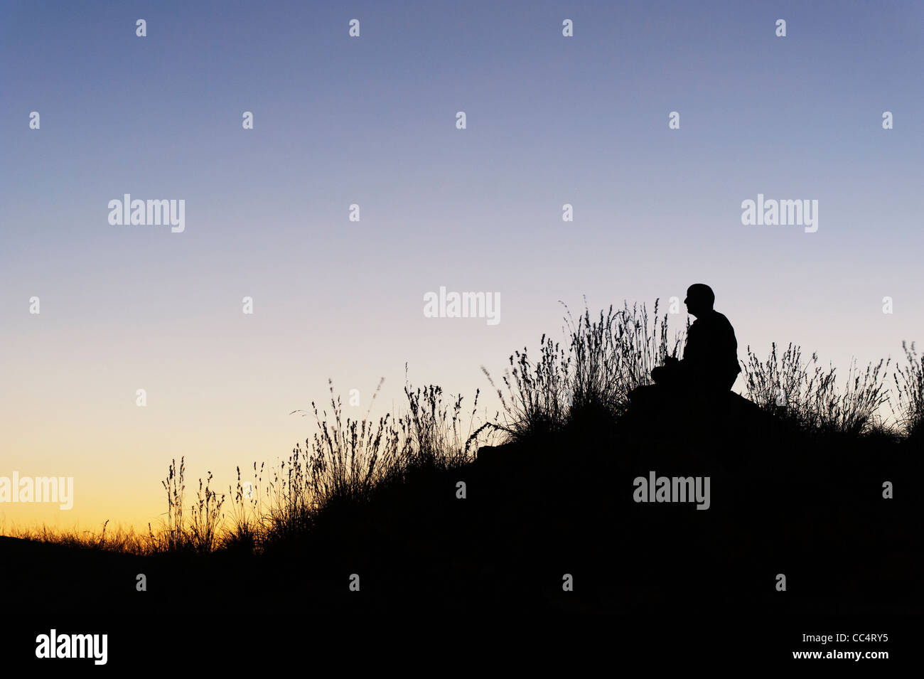 Man sitting in the indian countryside at dawn. Silhouette Stock Photo