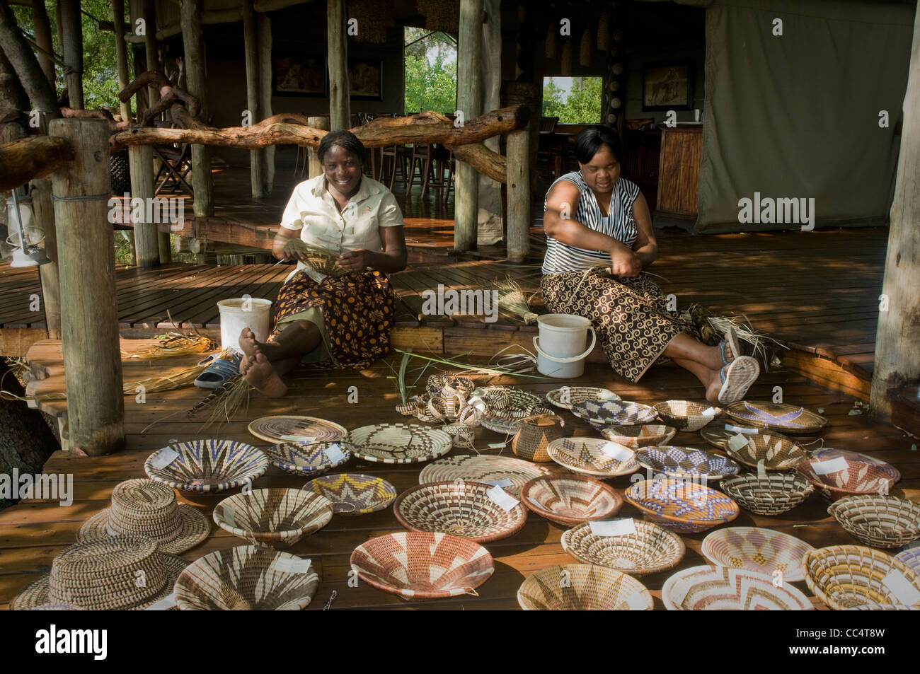 Africa Botswana Tuba TreeWomen weaving baskets, showing baskets in