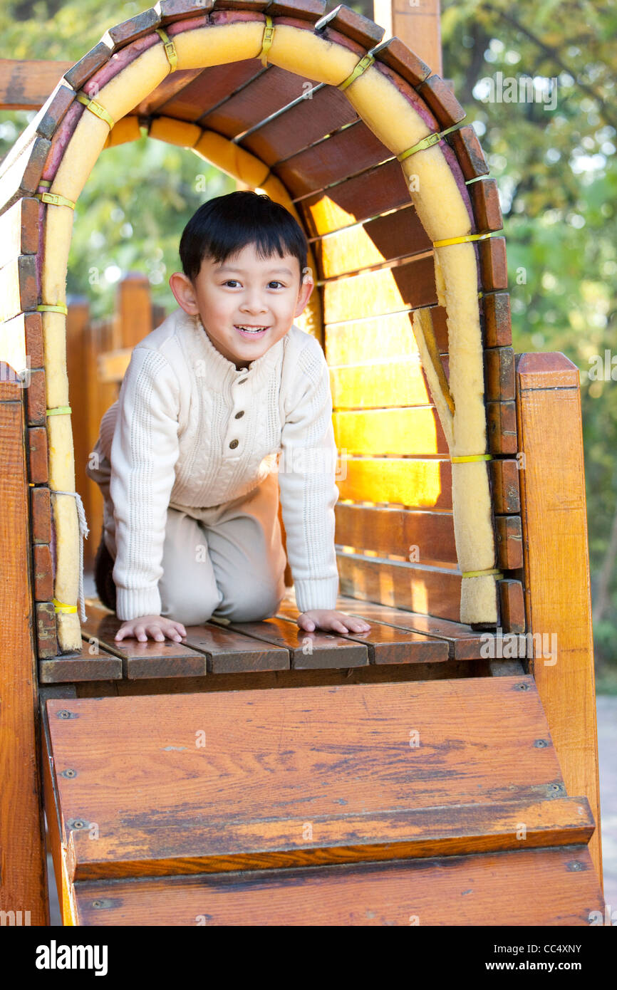 Boy crawling through tunnel in playground Stock Photo Alamy