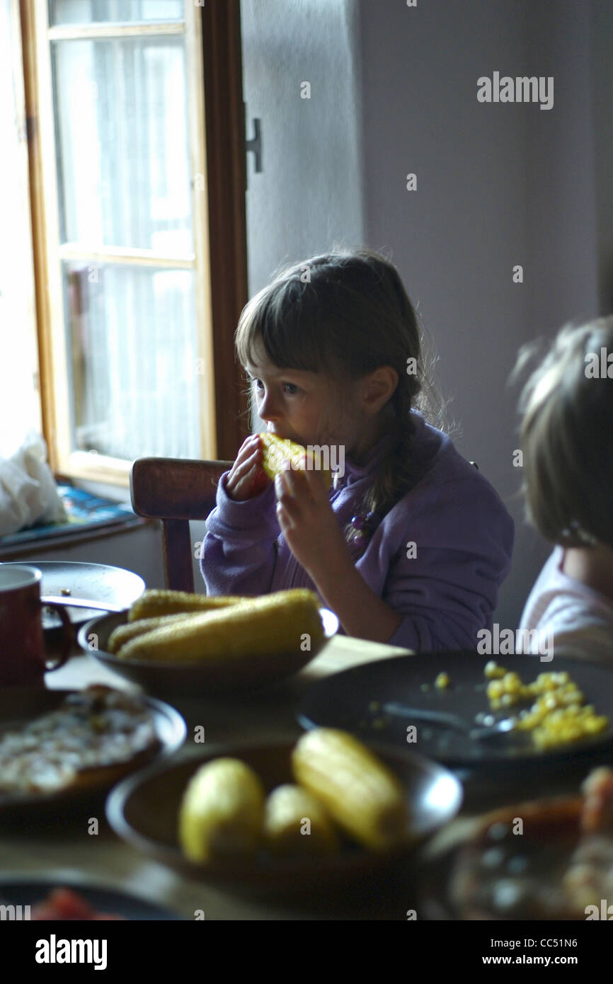 child eating sweetcorn in a kitchen Stock Photo