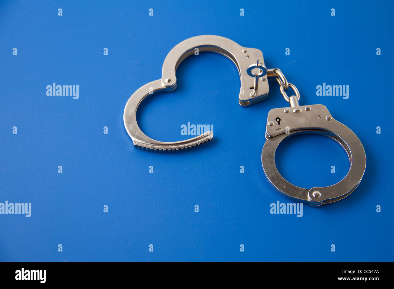 Open handcuffs with key on blue background Stock Photo