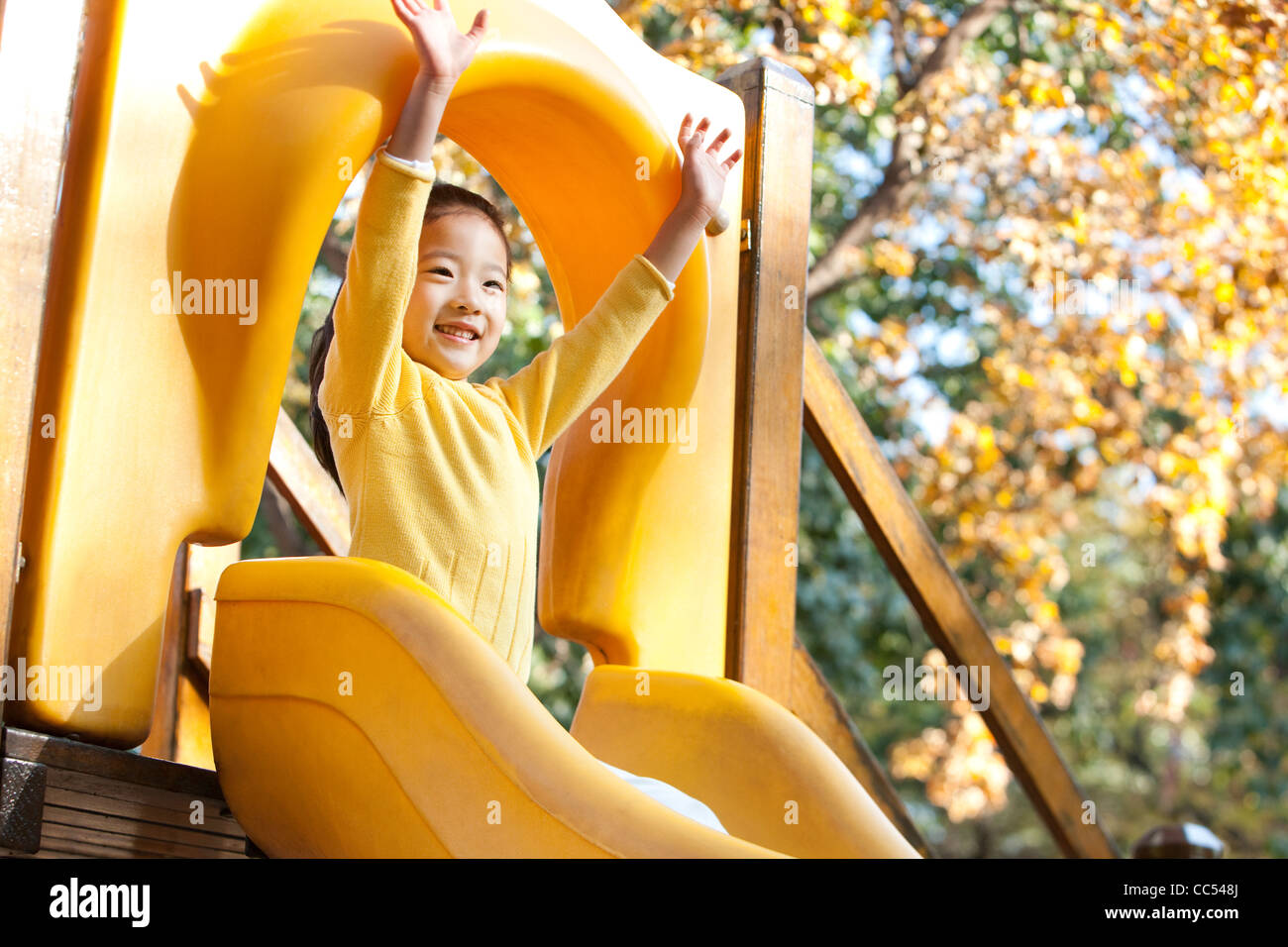 Girl playing on playground slide Stock Photo - Alamy
