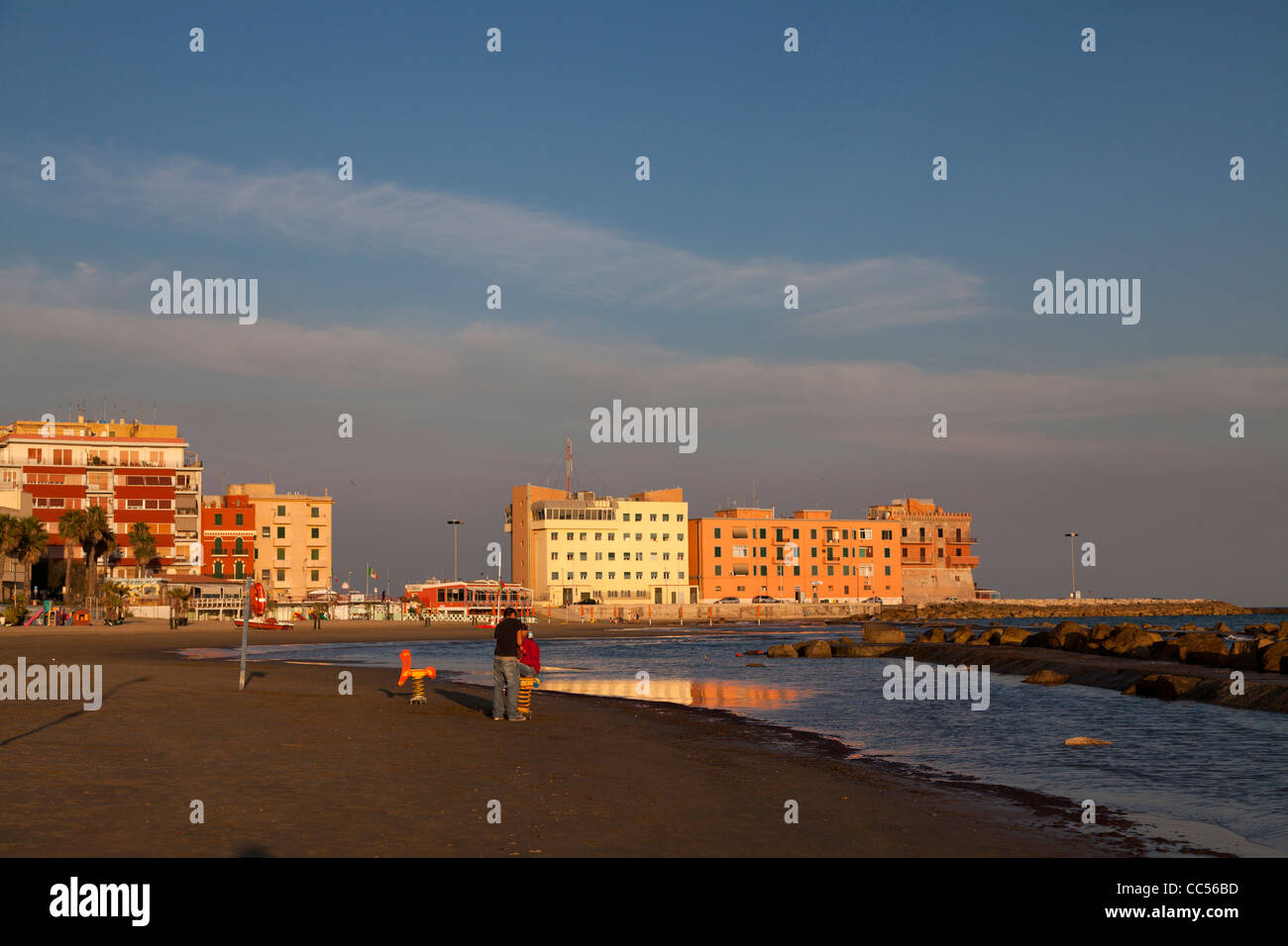 young couple alone on the deserted beach front at Anzio in the evening sun Stock Photo