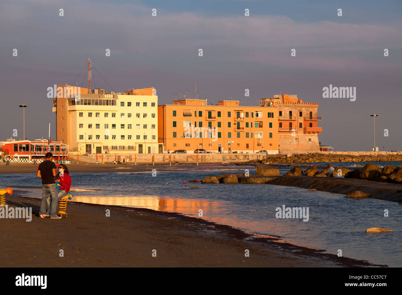young couple alone on the deserted beach front at Anzio in the evening sun Stock Photo