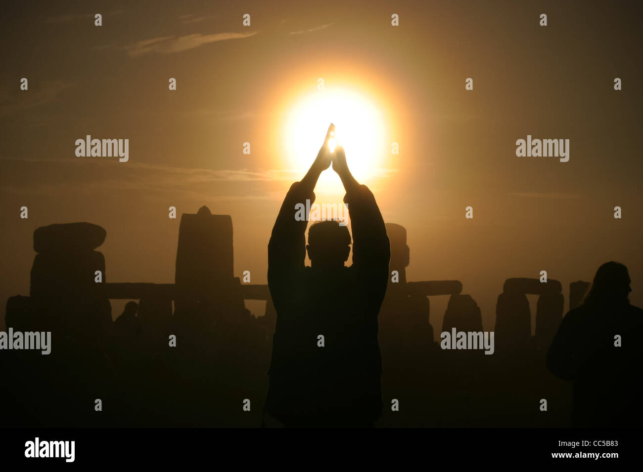 Celebrating the rising of the sun on the morning of the summer solstice at Stone henge, Wiltshire, UK Stock Photo