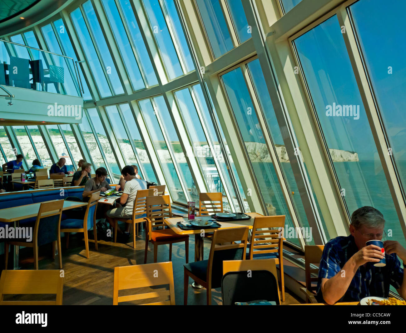 Passengers in the dining area of a cross channel ferry traveling from England to France with the White Cliffs of Dover behind Stock Photo