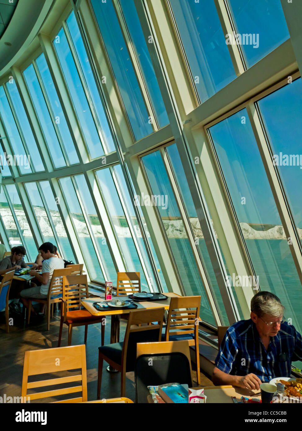 Passengers in the dining area of a cross channel ferry traveling from England to France with the White Cliffs of Dover behind Stock Photo