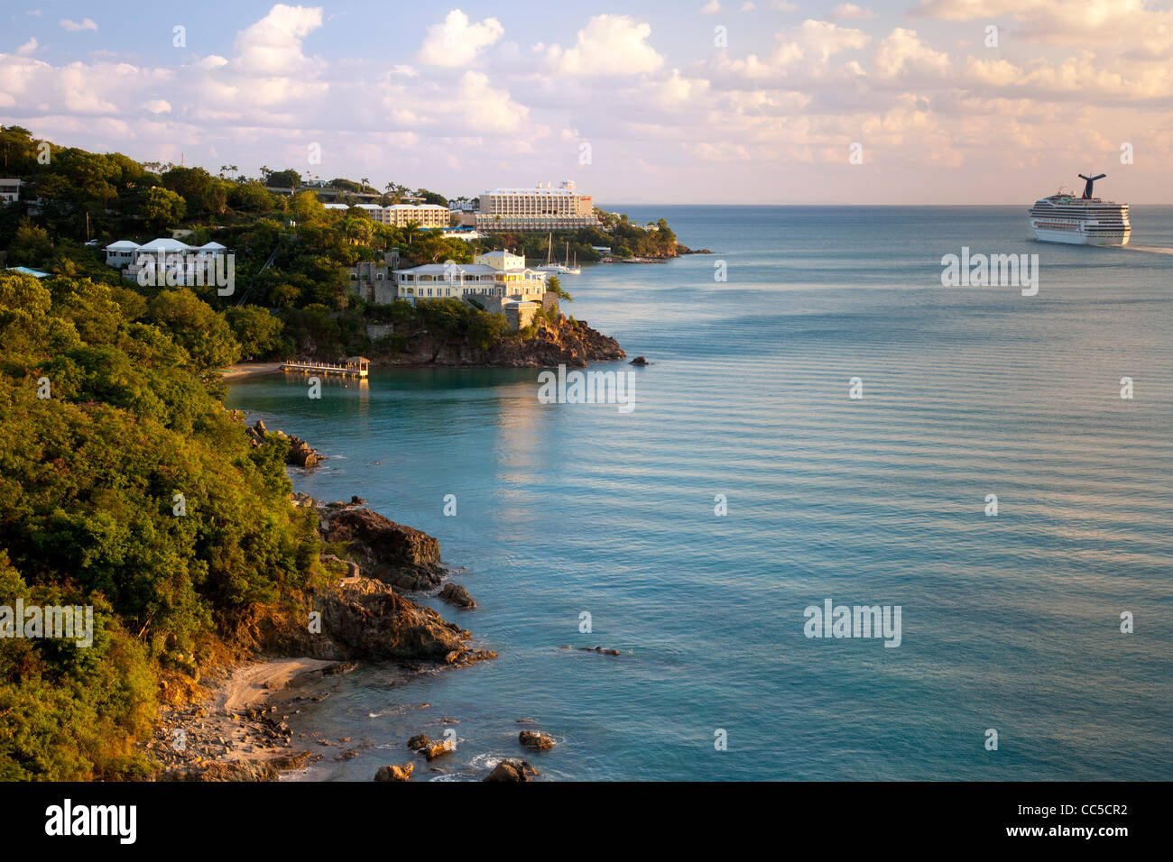 Cruise ship sails past Resort hotels in the setting sunlight along the coast of St Thomas, US Virgin Islands Stock Photo