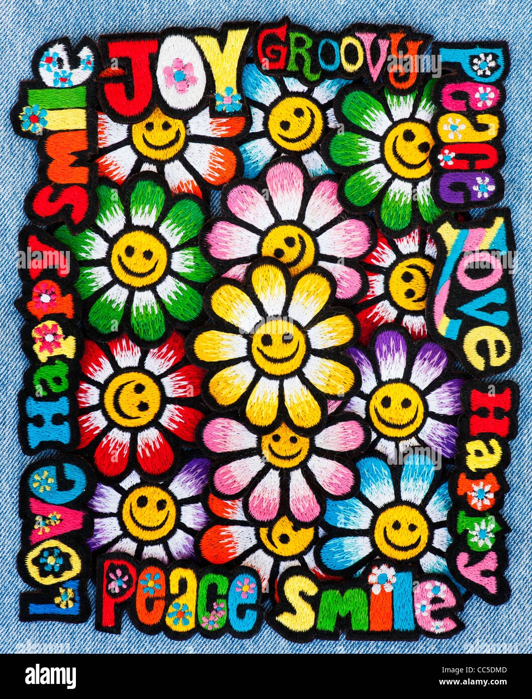 Embroidery iron on patches of Multicoloured Love, Peace, Happy words with smiley face flowers on a denim jean background Stock Photo