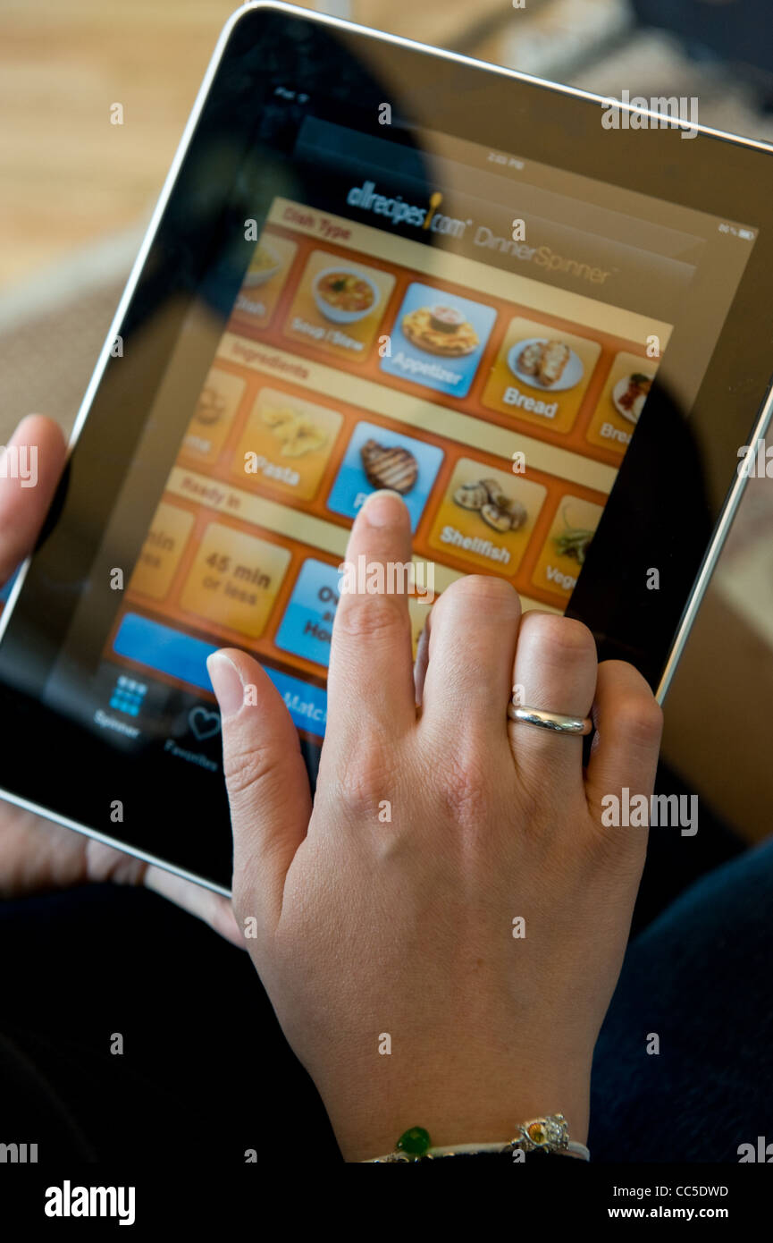 Caucasian woman uses Apple iPad to search food recipes on AllRecipes Stock Photo