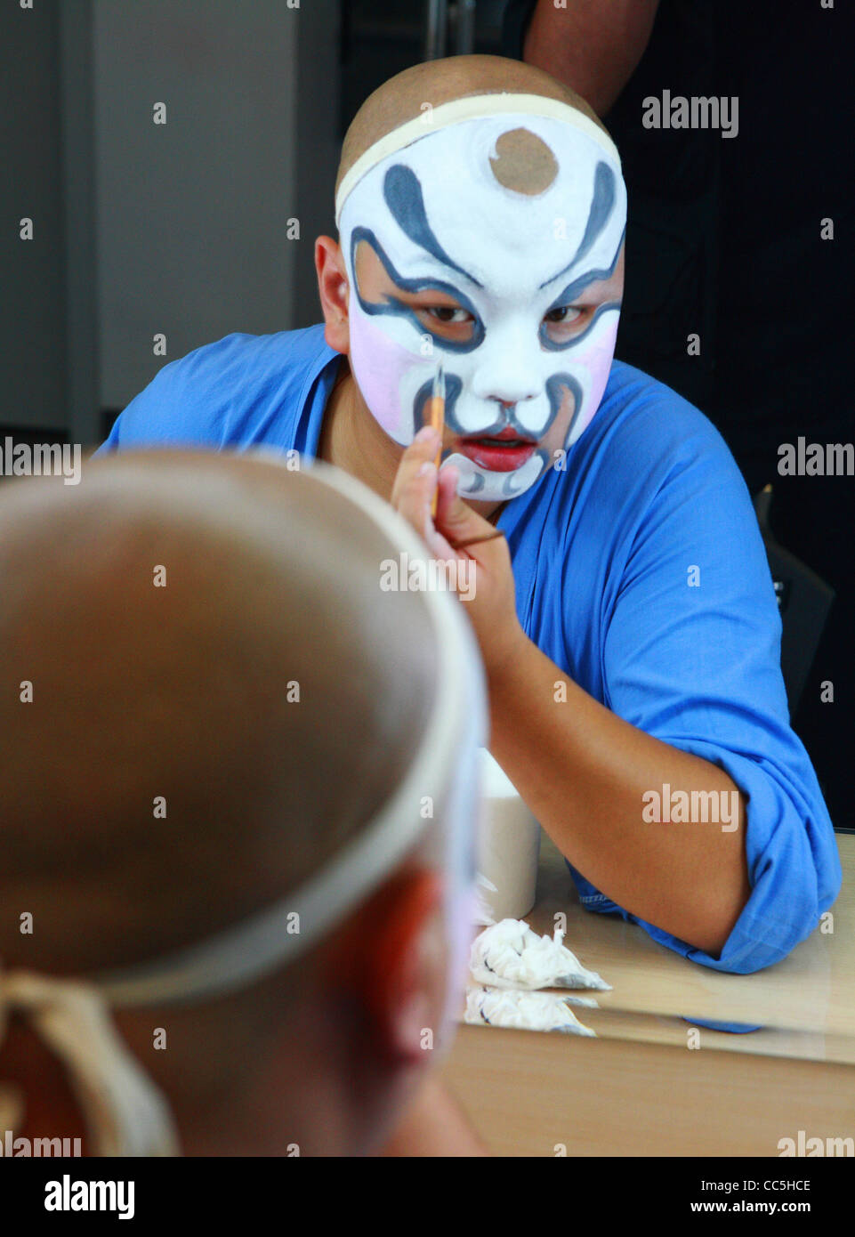 Male Peking opera performer painting his face, Beijing, China Stock Photo