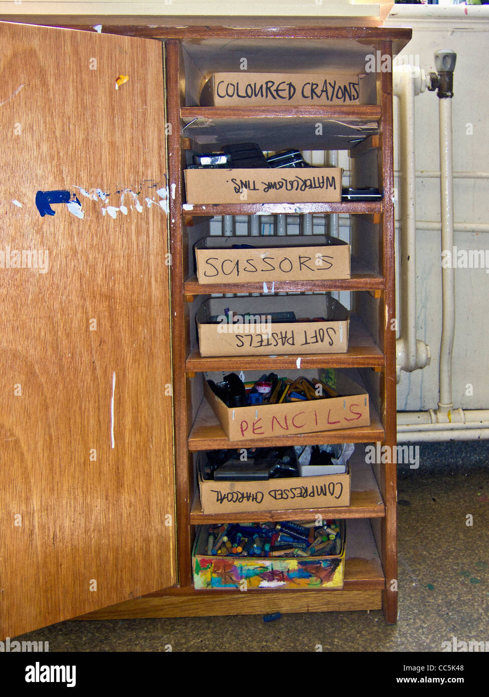 Shelves in wooden cupboard with boxes of art material, in an art studio. Stock Photo