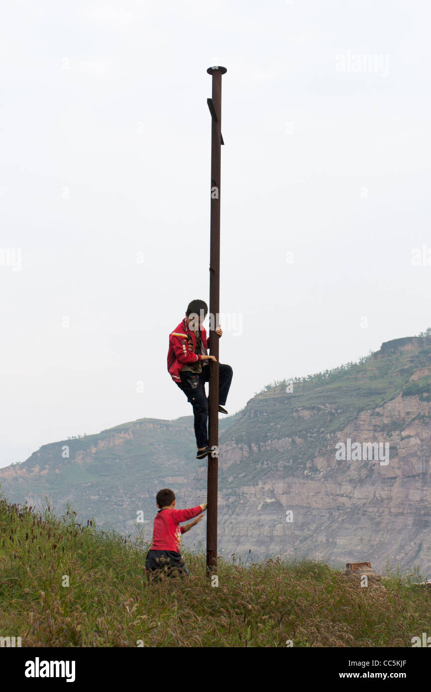 Boys climbing a pillar, Qikou Old Town, Lvliang, Shanxi , China Stock Photo