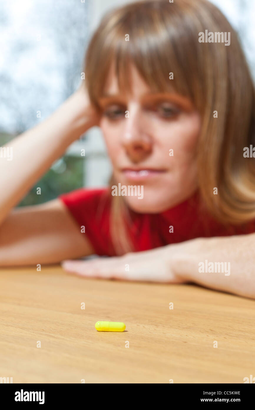 Woman with tablet. Deciding whether to take tablet. Stock Photo