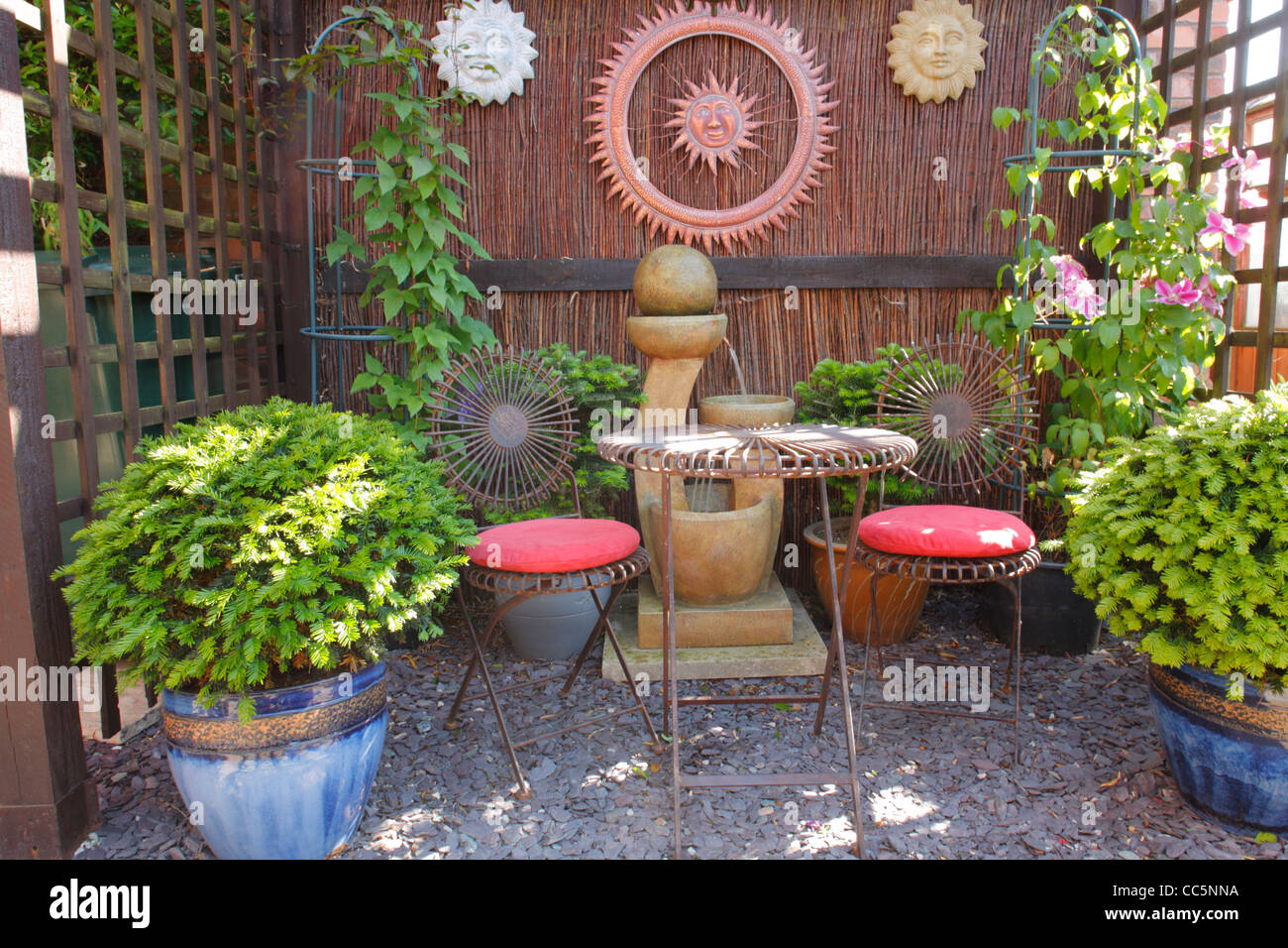 Arbor in an urban garden with table and chairs, potted plants and a water feature. Morecambe, England. June. Stock Photo