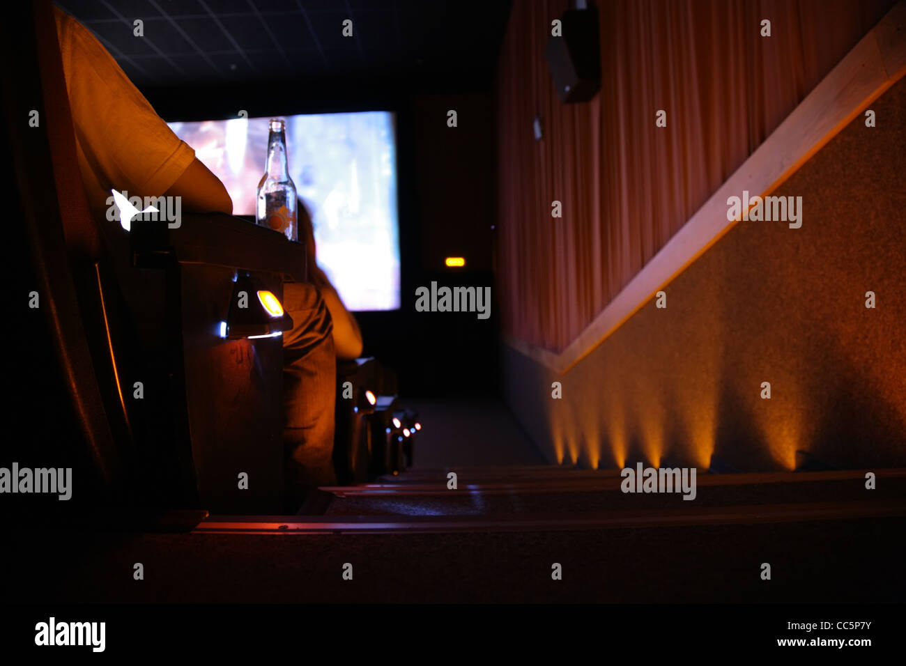 Behind spectator in cinema with bottle, focus on hand Stock Photo