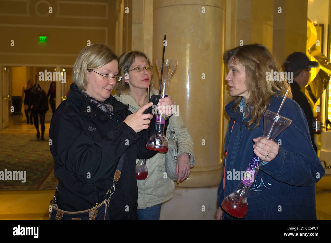 Three women with daiquiri vases enjoying Las Vegas nightlife in front of the Monte Carlo Hotel Stock Photo