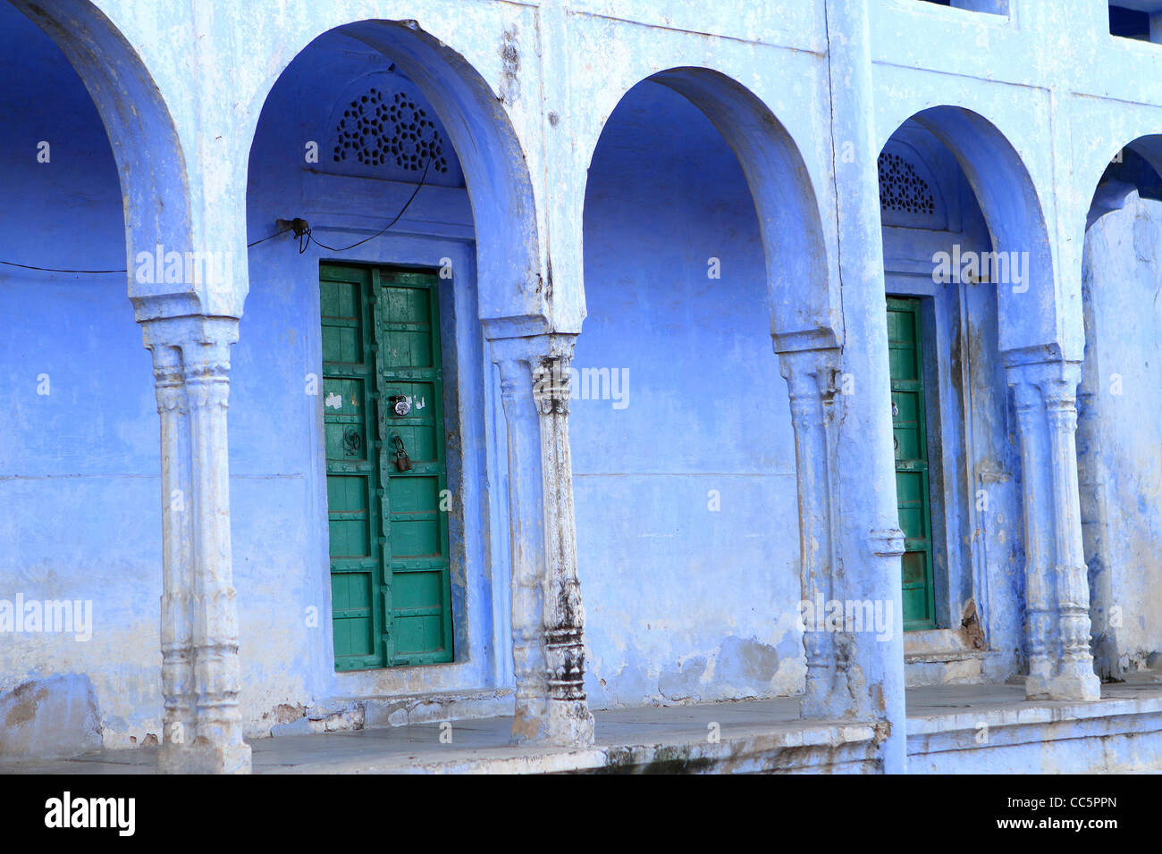Traditional Green wooden door and blue arches . Rajasthan. India Stock Photo