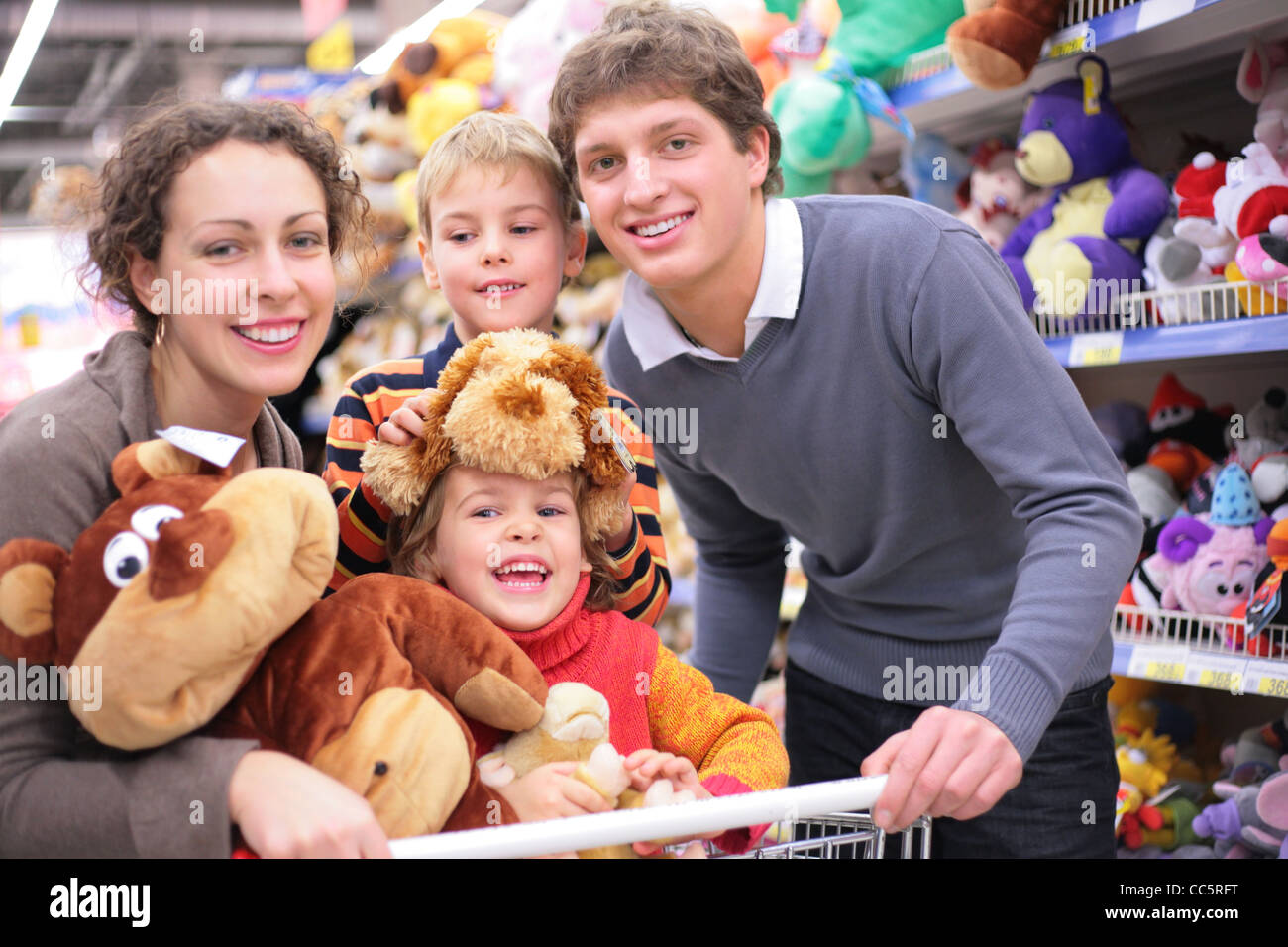 Family of four in shop with soft toys, focus on little girl Stock Photo