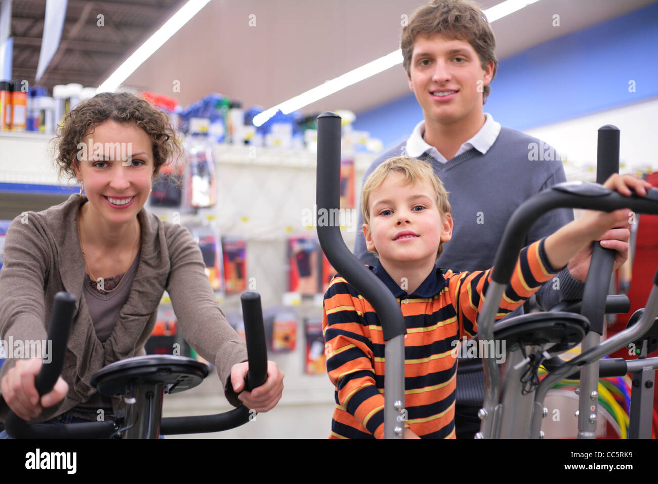 Parents with son on sports training apparatus in shop, focus on boy Stock Photo