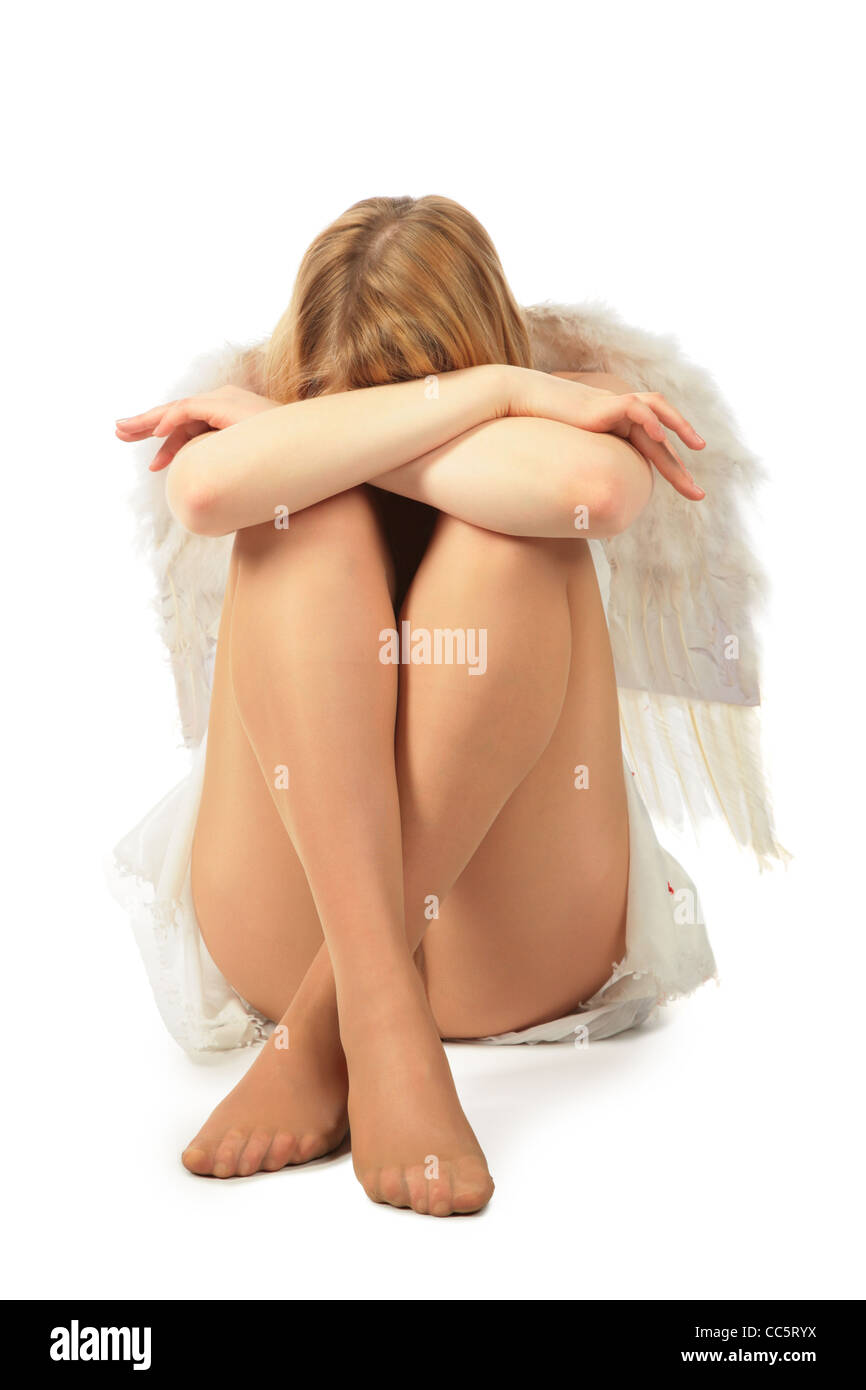 girl in angel's costume sits face in knees and having closed by hands Stock Photo