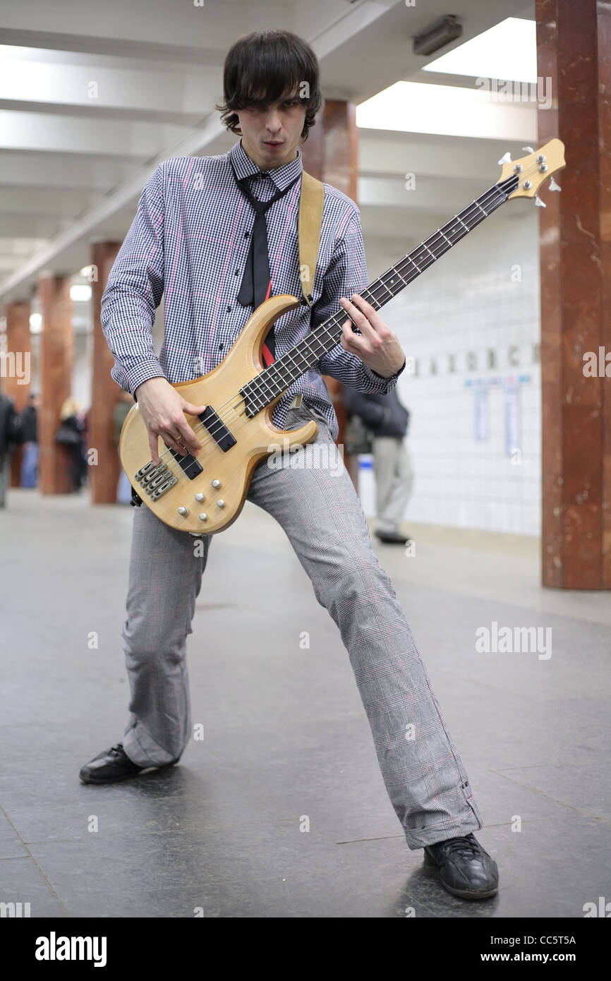 young musician play on guitar at metro station, focus on strings Stock Photo