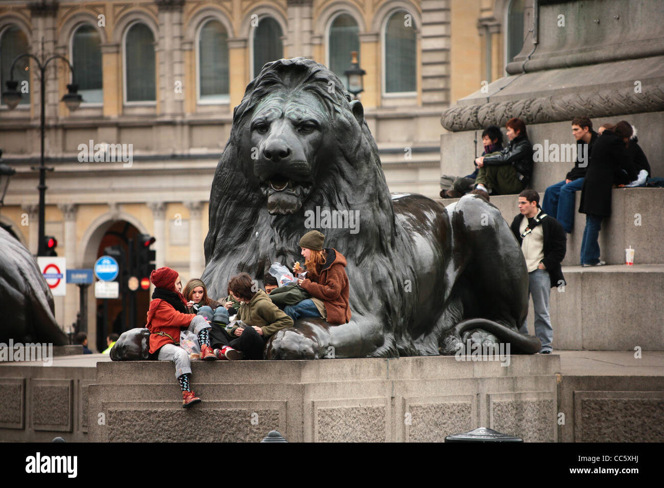 A family enjoys a picnic on one of the famous landmarks, one of the Lion statues in Trafalgar Square, London, England. Stock Photo