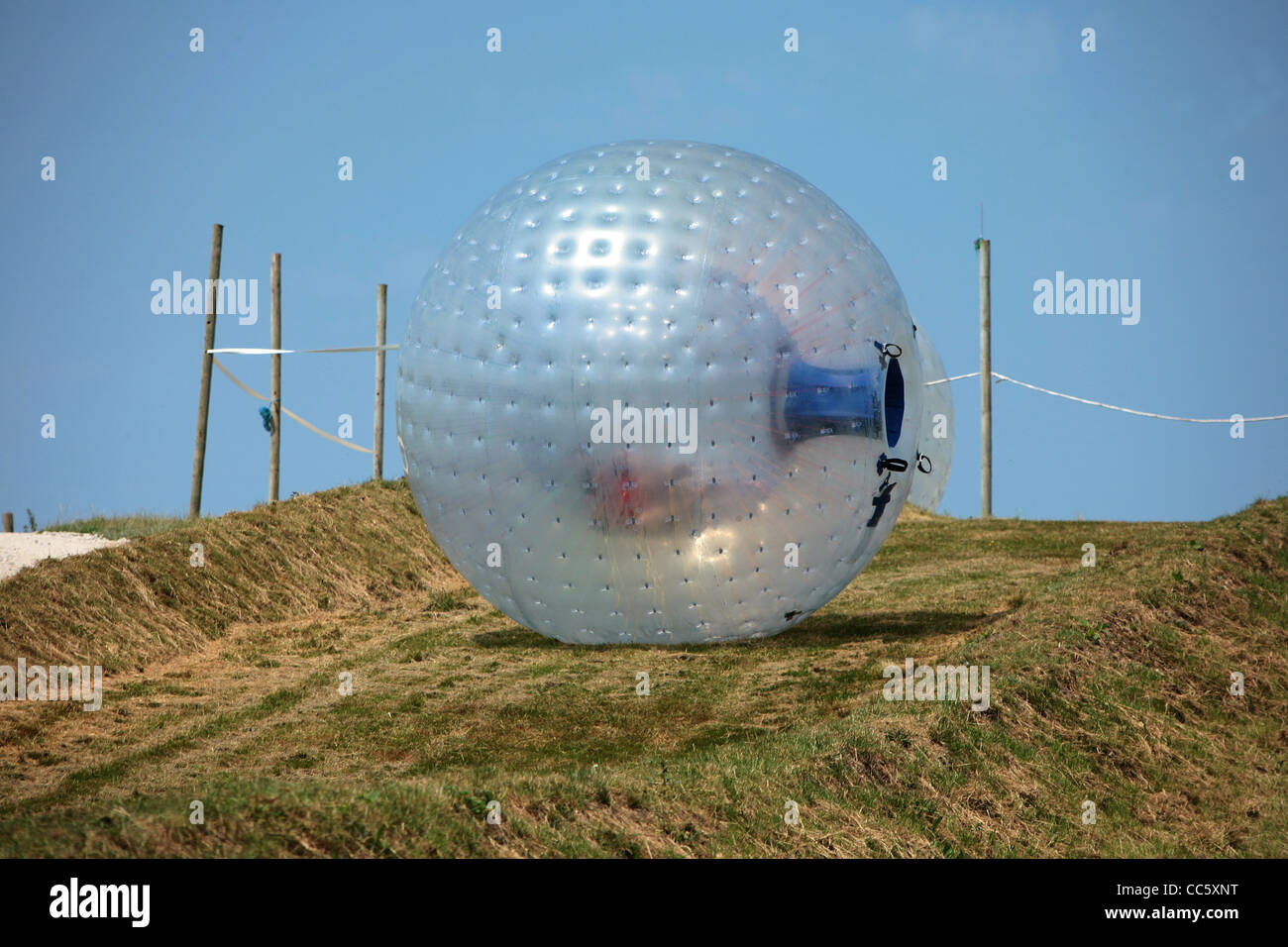 People enjoy Zorbing or Sphering on a hill in Dorset England. Stock Photo