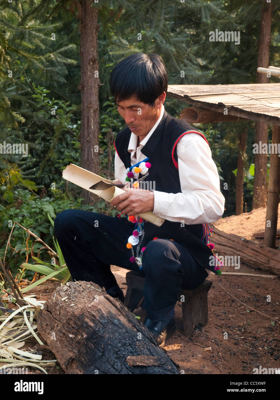 Hani man making a bamboo tube, Mahei Village, Yiwu, Xishuangbanna, Yunnan , China Stock Photo