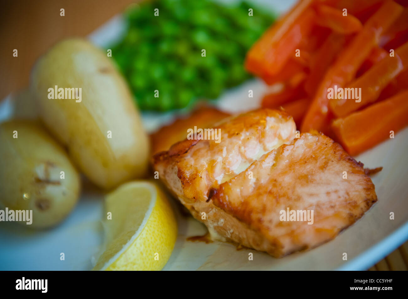 Scottish salmon with boiled potatoes, peas, lemon and carrots Stock Photo