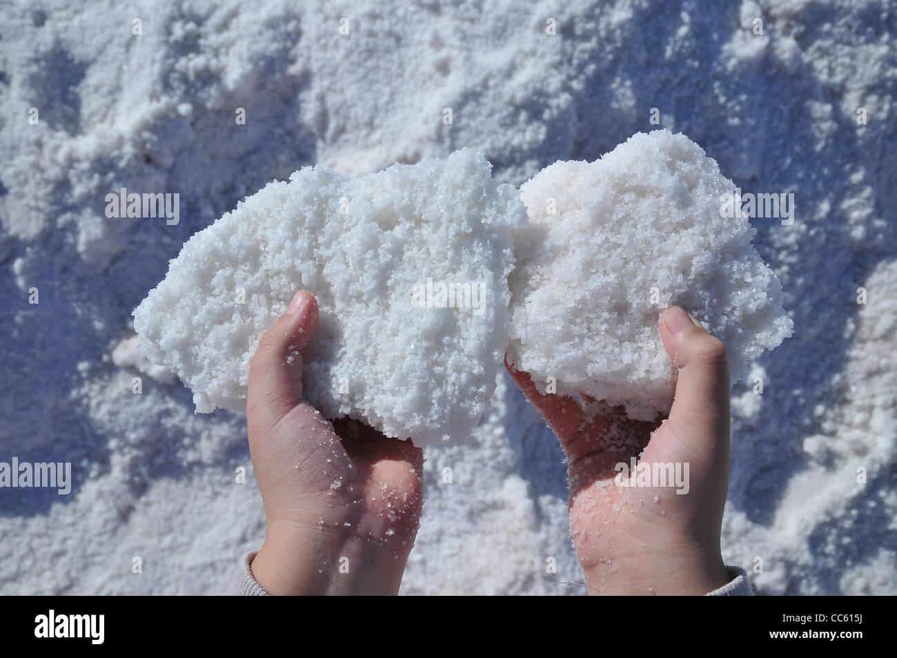 Hands of a young girl holding sea salt from the dehydration pools Stock Photo
