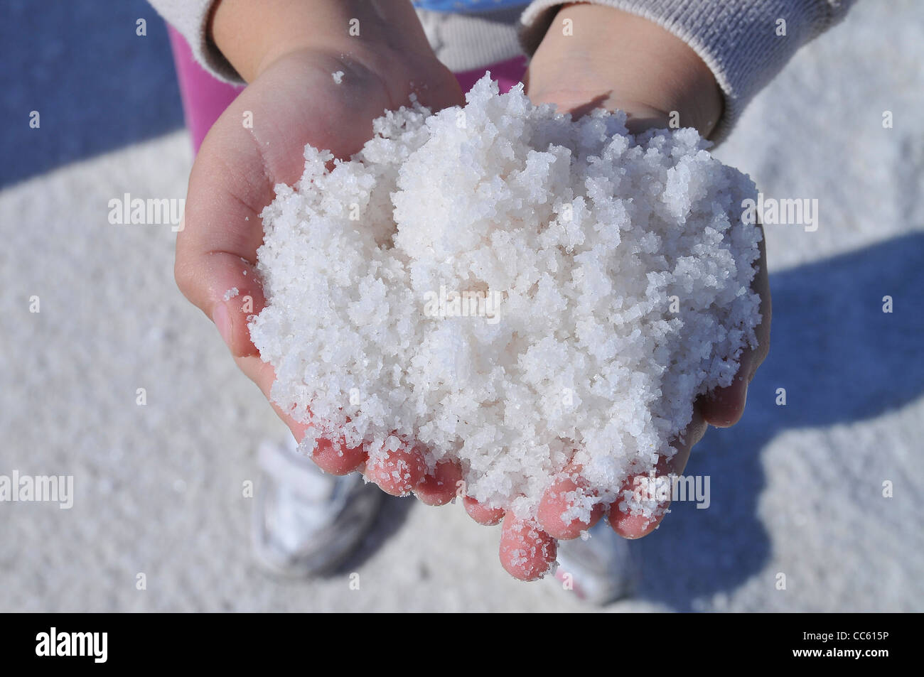 Hands of a young girl holding sea salt from the dehydration pools Stock Photo